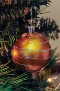 Cramer Imaging's macro or closeup photograph of a golden Christmas ornament hanging on a Christmas tree