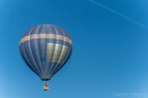 Cramer Imaging's fine art photograph of a blue hot air balloon taking flight in Panguitch Utah with a blue morning sky with contrail