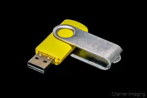 Stock photograph of a yellow flash drive, thumb drive, or jump drive on a black background