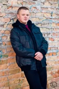 Portrait of a teenage boy modeling against a rough brick wall