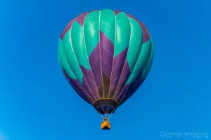 Cramer Imaging's fine art photograph of a purple and teal hot air balloon drifting in the sky