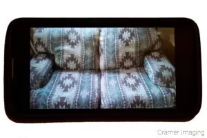 Cramer Imaging's photograph of a black smart phone displaying a patterned couch or furniture picture on the screen