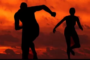 male and female silhouettes running against a fiery sunset background