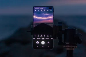 Photograph of a cell phone taking a sunset seascape photo while stabilized on a tripod