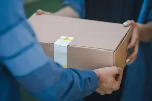 Photograph of a package delivery in person from a man to a woman