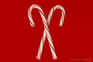 Cramer Imaging's professional quality holiday or Christmas product photograph of two crossed candy canes on a red background