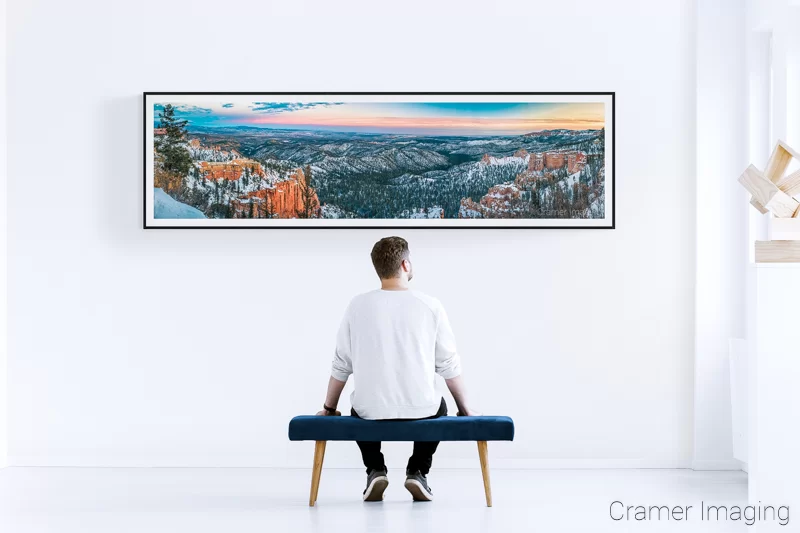 Photo of Cramer Imaging's "Skyview" panorama on a white gallery wall with a man sitting in front