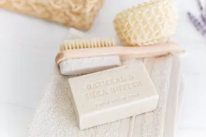 Photograph of a bar of soap and a scrubbing brush sitting on a wash cloth