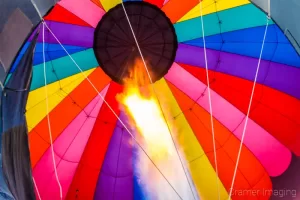 Fine art photograph of a flaming jet shooting up a colorful hot air balloon in Panguitch, Utah by Cramer Imaging