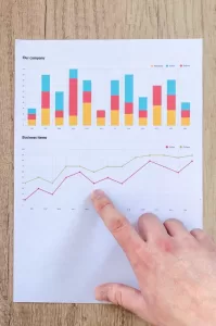 Photograph of a right hand pointing to some statistics graph of a piece of paper