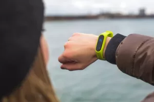 Photo of a woman looked at a green smart watch or fitbit on her right wrist