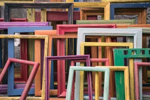 Photograph of lots of colorful empty picture frames stacked up in a pile