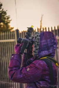 Professional photographer Audrey Cramer taking a picture standing next to a fence