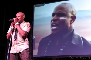 Cramer Imaging's professional quality concert photograph of singer Alex Boyé in scout uniform in person and on screen in Firth Idaho