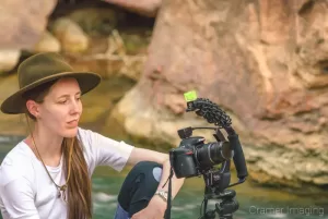 Photograph of landscape photographer Audrey Cramer checking the back of her camera on a photo shoot