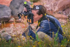 Behind-the-scenes photo of landscape photographer Audrey Cramer crouched down in the weeds for a photo