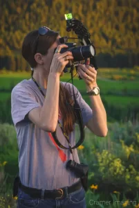 Landscape photographer Audrey holding up a camera and taking a picture by Cramer Imaging