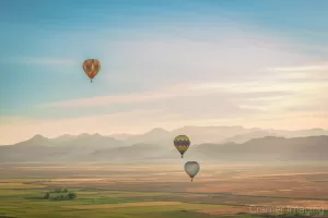 Cramer Imaging's fine art aerial photograph of three hot air balloons flying over a field in Panguitch Utah with a blue partly cloudy sky