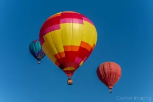 Cramer Imaging's fine art photograph of three colorful hot air balloons taking flight in Panguitch Utah with a blue morning sky