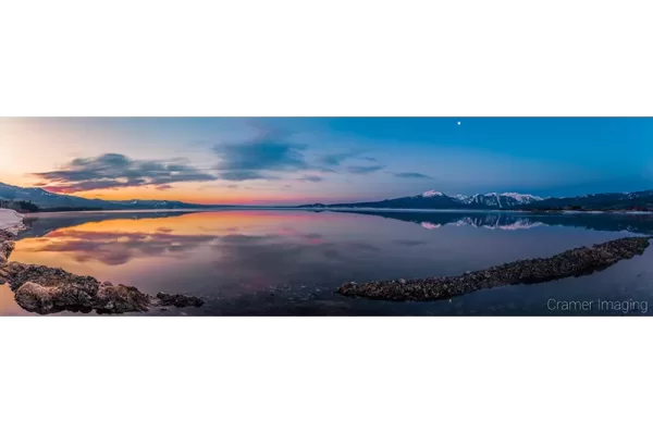 Cramer Imaging's professional quality landscape panorama photograph of the sky and moon reflecting in Henry's Lake at dawn with blue and golden hours