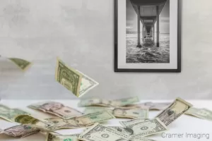 Photograph of falling money on a table and Cramer Imaging's fine art landscape photo titled "San Diego Pier"