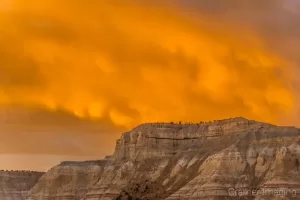 Cramer Imaging's fine art landscape photograph of fiery orange fireball in the clouds above the mountains of Cannonville Utah