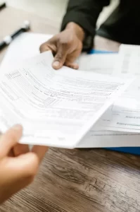 Photograph of two people handling tax forms across a table