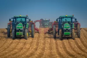 Photograph of John Deer tractors harvesting potatoes from a potato field in Aberdeen Idaho as taken by Cramer Imaging