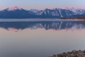 Cramer Imaging's professional quality landscape photograph of mountains and a cabin reflecting in Henry's Lake at dawn