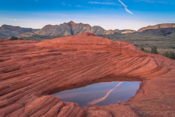 Cramer Imaging's fine art landscape photograph of a hidden pool atop layered red rocks reflecting the sky in Snow Canyon State Park, Utah