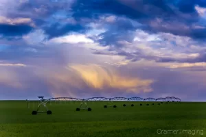 Cramer Imaging's professional quality landscape photograph of a farm field and equipment with colorful clouds in Rexburg, Madison, Idaho