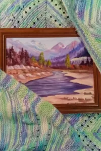 Photograph of a framed landscape painting wrapped in a knit blanket for protection while moving by Cramer Imaging