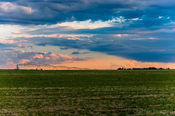 Cramer Imaging's fine art landscape photograph of a cloudscape at sunset over a farm field with irrigation equipment in Burley Idaho