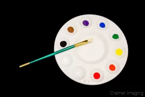 Cramer Imaging's stock photograph of paint, a paintbrush, and a palette on a black background