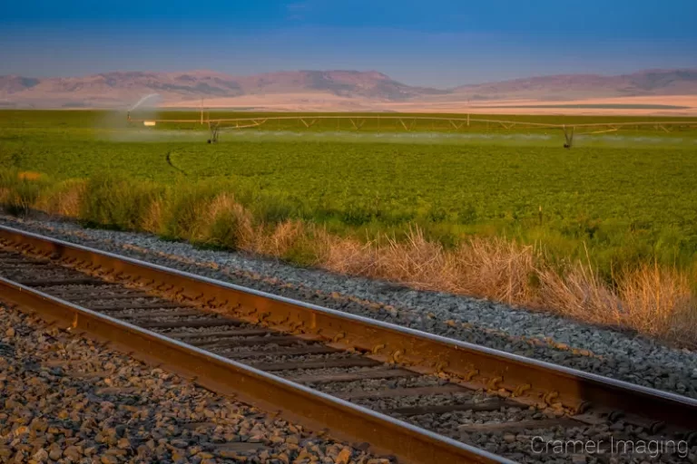 Cramer Imaging's photograph of a potato field getting watered in American Falls, Idaho with railroad tracks in front