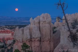 Cramer Imaging's fine art landscape photograph of a red moon rising over rock formations of Bryce Canyon National Park Utah