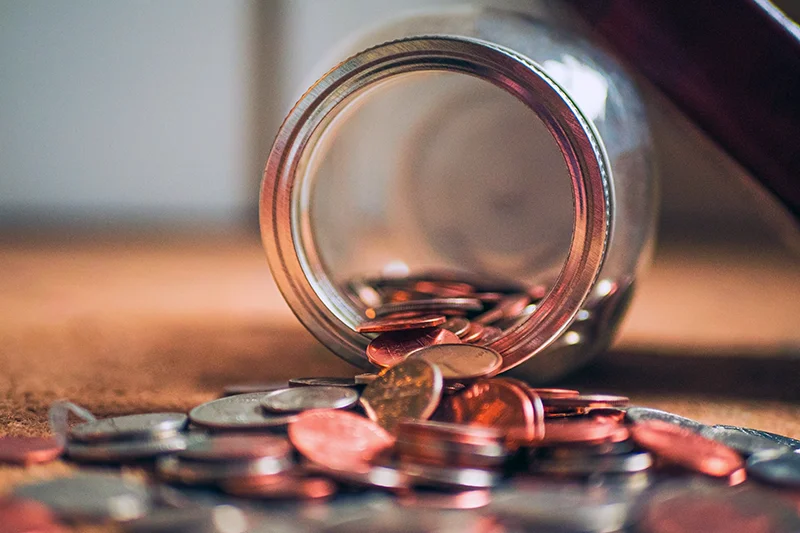 Photograph of a jar filled with American coins spilled out onto the floor