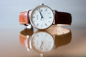 Photograph of a men's wrist watch sitting on a mirrored surface