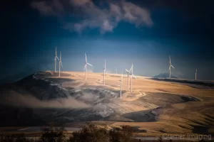 Cramer Imaging's fine art landscape photograph of wind turbines on hill in golden light of sunset just after winter snow storm