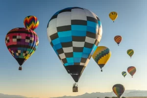 Fine art photograph of a cluster of hot air balloons rising into the sky at dawn in Panguitch, Utah by Cramer Imaging