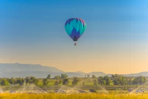 Fine art photograph of a single hot air balloon flying over a farm field in Panguitch, Utah by Cramer Imaging