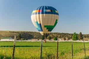 Fine art photograph of a hot air balloon drifting low above a farm field in Panguitch, Utah by Cramer Imaging