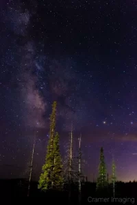 Cramer Imaging's fine art astrophotography photograph of the Milky Way in the night sky with clouds and light painted trees