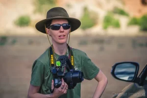 Photo of landscape photographer Audrey Cramer holding her camera standing next to a car