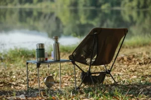 Photograph of a backpacking or camping chair with bottles sitting on table out in nature