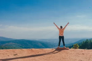 Photograph of a young hiker atop a cliff celebrating the achievement