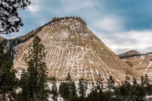 Cramer Imaging's fine art landscape photograph of a snow-covered Checkerboard Mesa with cloudy skies at Zion National Park Utah