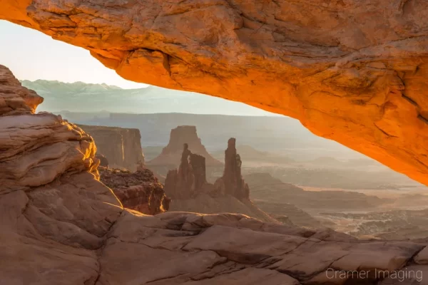 Cramer Imaging's fine art landscape photograph of the Washer Woman arch seen through Mesa Arch at sunrise in Canyonlands National Park, Utah