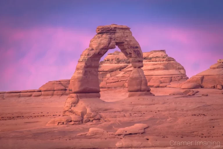 Cramer Imaging's fine art landscape photograph of a cotton candy pink sunset behind Delicate Arch at Arches National Park, Utah