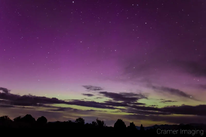 Audrey Cramer Photography's fine art astrophotography photograph of an aurora borealis appearing in the night sky with clouds